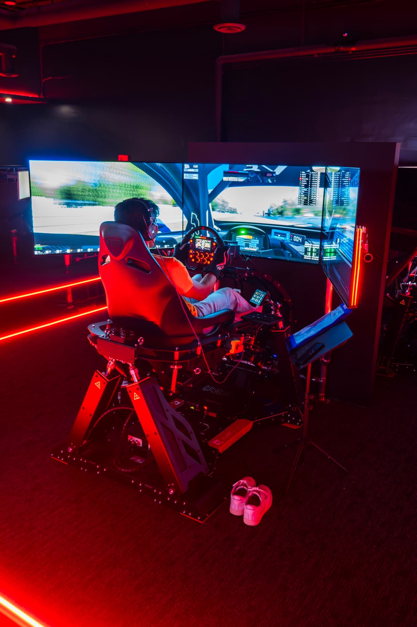 Driver from behind at a WOR Tustin rig, mid-session under the neon-track ceiling