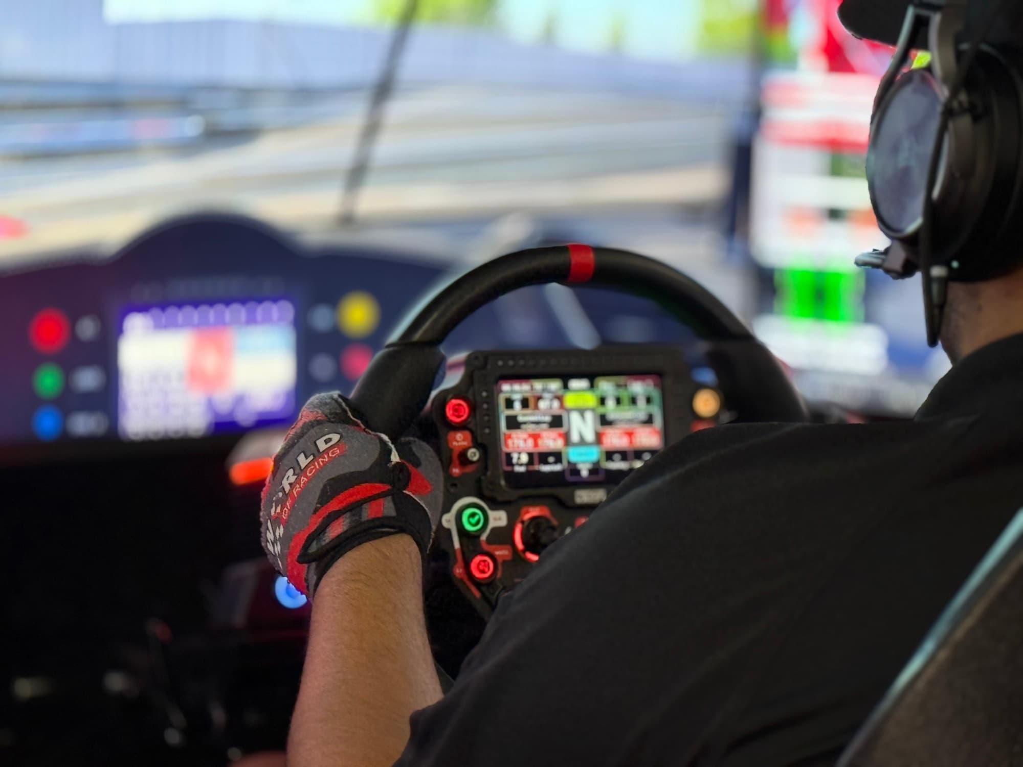 Driver's view of a force-feedback wheel with a live data display, mid-race