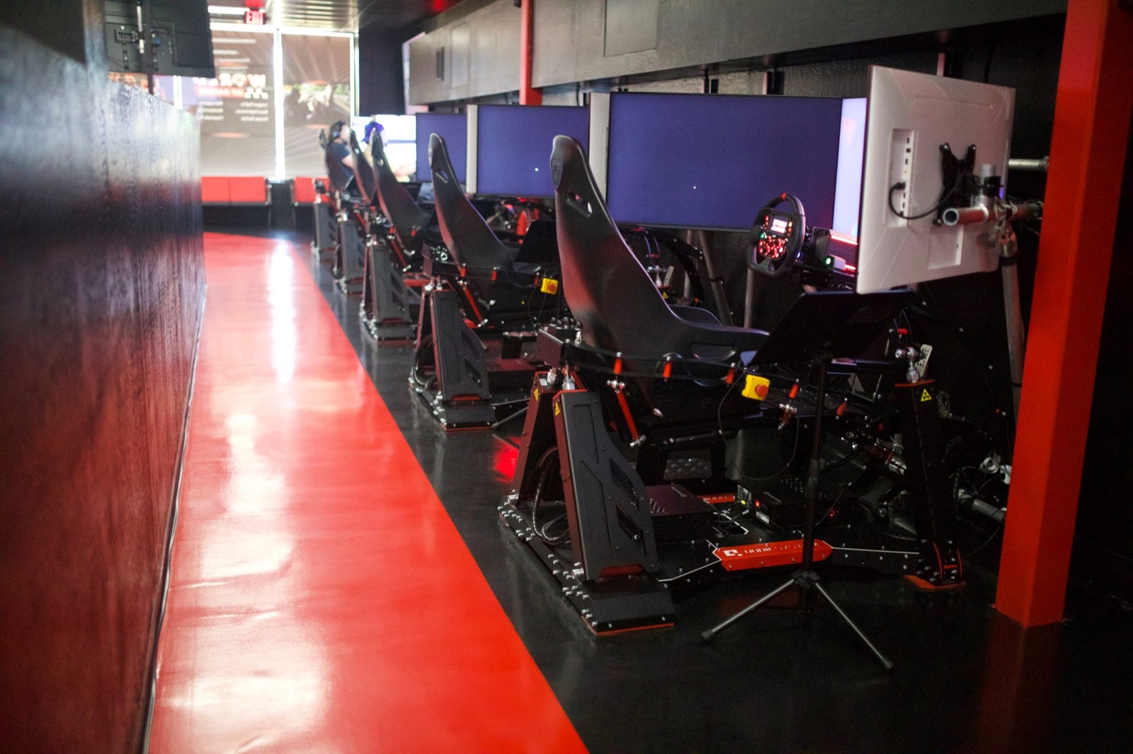 Row of full-motion World of Racing sim rigs with racing seats and force-feedback wheels
